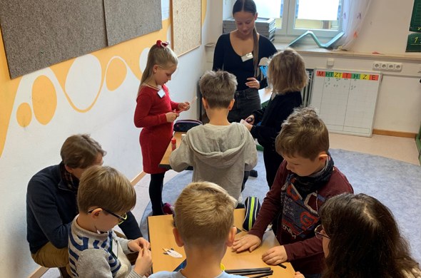 Kindergruppe an Tischen mit Lehrerin basteln