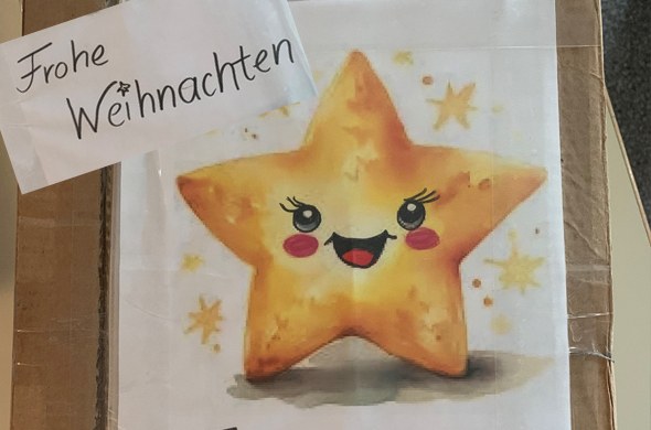 Lachender Stern als Comicfigur mit Schild Frohe Weihnachten