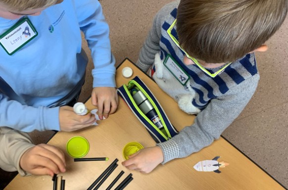Kinder stehen um einen Tisch und basteln