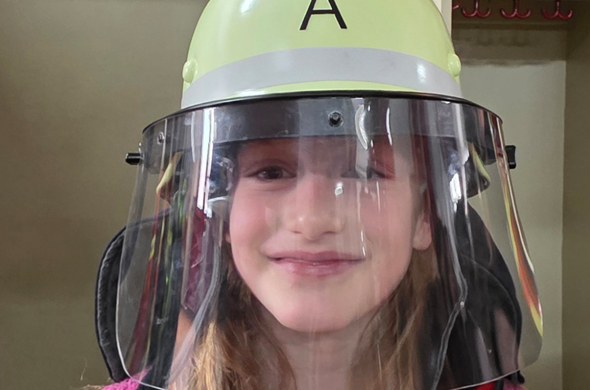 Schülerin trägt Feuerwehrhelm und lacht