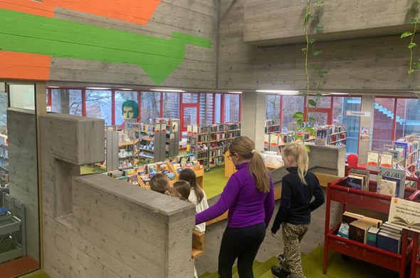 Schueler gehen Treppe in Bücherei hinunter in Bücherabteilung