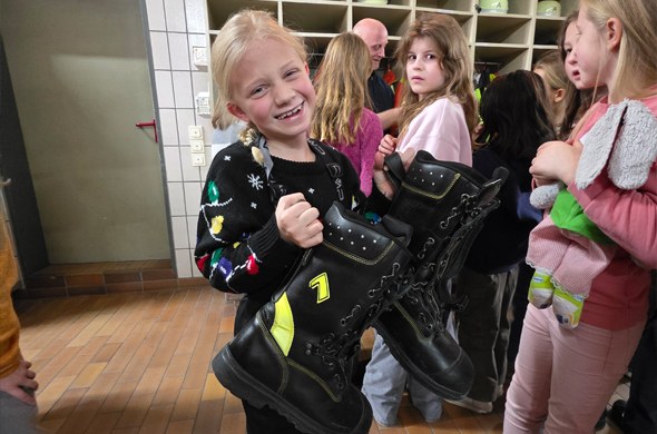 Schülerin hält grosse Feuerwehrstiefel in der Hand