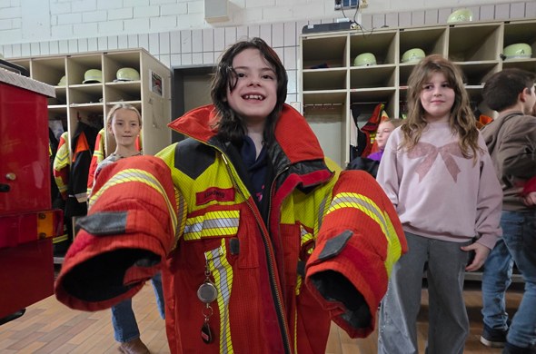 Mädchen in zu grosser Feuerwehruniform in der Feuerwehrhalle