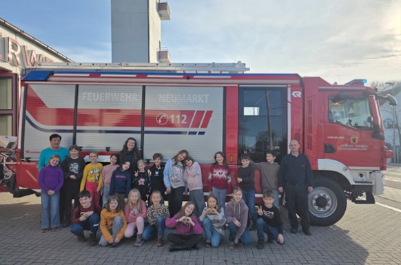 Gruppenfoto der Schulklasse vor dem Feuerwehrauto im Hof