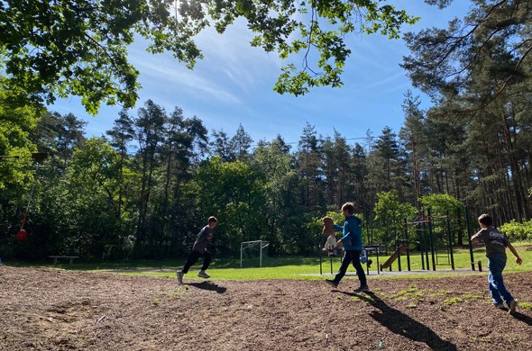 Mehrere_Schulkinder_spielen_Fangen_auf_einem_Waldspielplatz