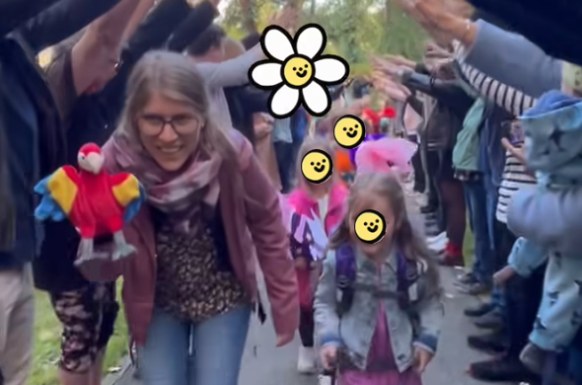 Erstklässler gehen mit Lehrerin durch ein Spalier aus Händen und sind fröhlich