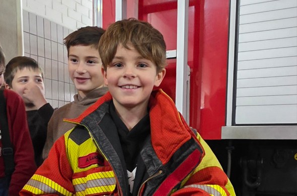 Schüler in zu grosser Feuerwehrjacke mit Schulfreunden