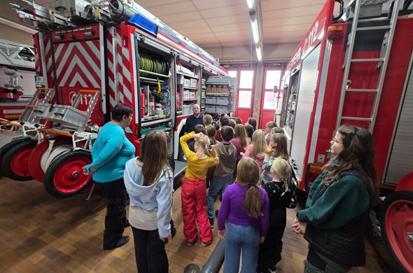 Schulkinder in der Feuerwehrhalle Feuerwehrmann erklärt Equipment