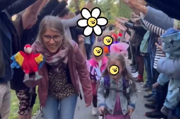 Erstklässler gehen mit Lehrerin durch ein Spalier aus Händen und sind fröhlich