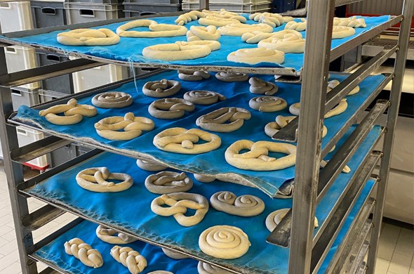 Brezenteiglinge liegen zum backen auf Bleche bereit