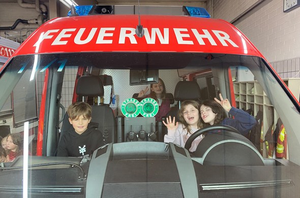 Kinder in Feuerwehrauto schauen vorne raus und haben Spaß