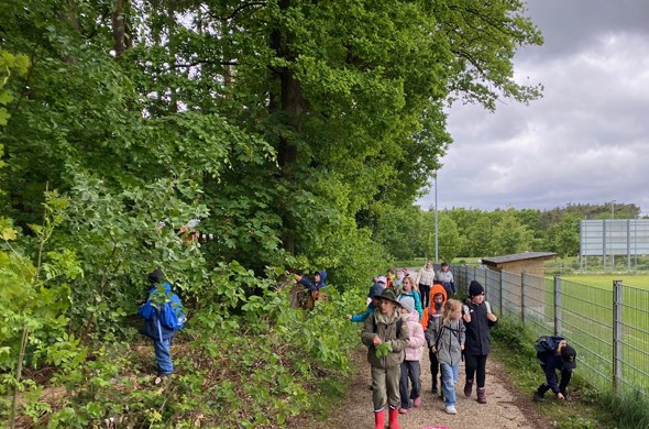 Schueler_wandern_mit_Rucksack_am_Waldrand_entlang_zum_Ausflug