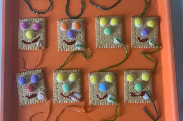 Butterkekse auf Tablet mit bunten Smarties Gesichternverziert